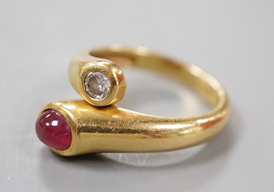 A modern 18k, cabochon ruby and round cut diamond set crossover ring, size N, gross weight 6.8 grams.